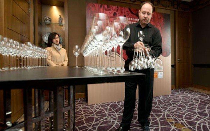 بالصور.. بريطاني يحمل 51 كأساً بيد واحدة