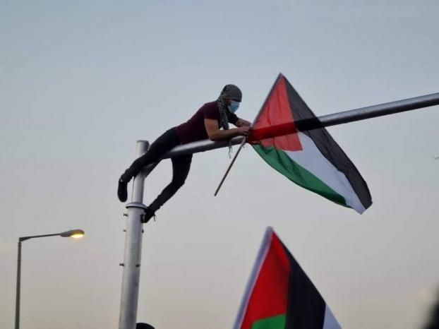 ترفض أن تكون إلا فلسطينية.. شاب يرفع علم فلسطين خلال تظاهرة ضد جرائم الشرطة في مدينة طمرة بالداخل